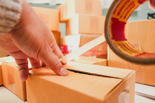 Goods delivery concept , Human hand packs merchandise into cardboard box for delivery to a customer photo