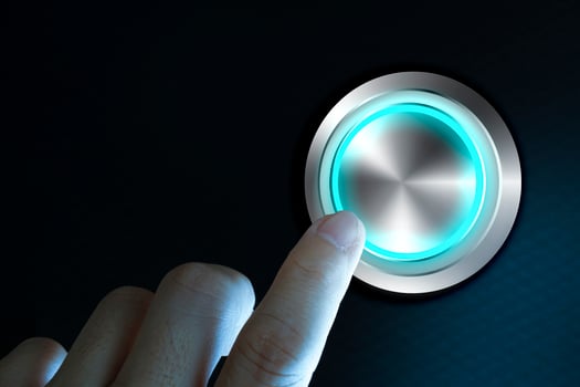Finger about to press button with blue light over black and grey background. photo