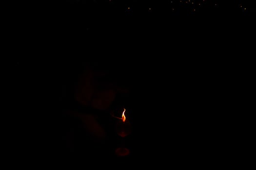 A person is holding a candle in a dark room. The candle is lit and the room is dimly lit photo