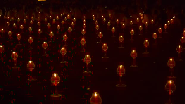 A large number of candles are lit at borobudur temple. The candles are arranged in a pattern, with some candles grouped together and others spaced apart. Scene is one of warmth and coziness photo
