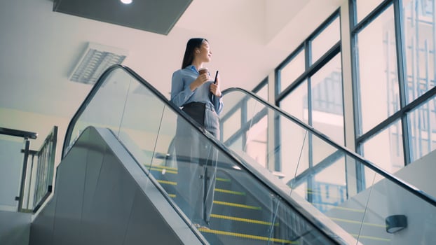 A business woman is walking down to escalator with a coffee cup in her hand photo