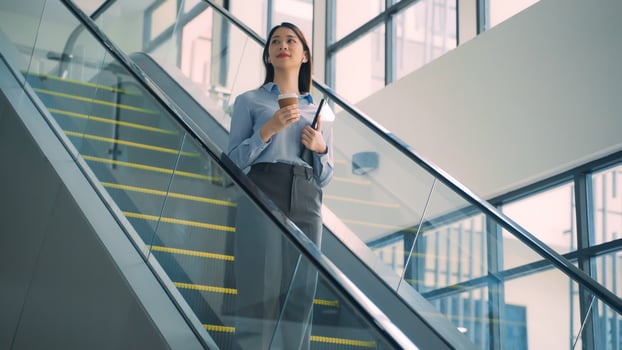 A business woman is walking down to escalator with a coffee cup in her hand photo