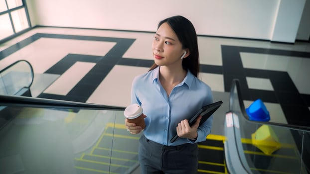 A business woman is walking up to escalator with a coffee cup in her hand photo