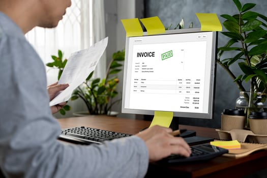 Hands of businessman analyzing invoice on laptop while checking bills. Rear view of latin man checking invoice while matching them on computer. photo