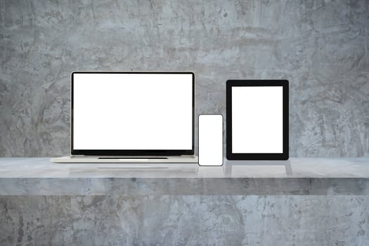 Laptop, mobile phone and digital tablet pc on grey wall shelf. photo