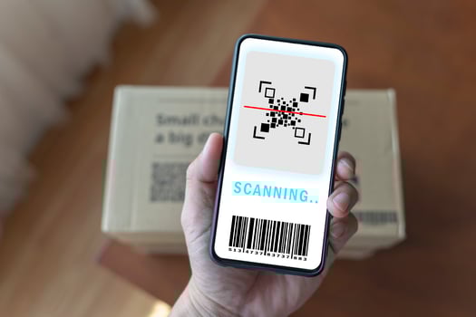 close up of man's hand with smartphone scanning barcode on parcel box at post office photo