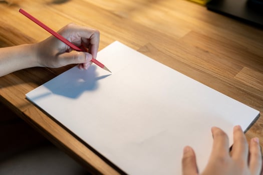 Woman writing something on sheet of paper at workplace in evening.Free space can contain advertising messages. photo