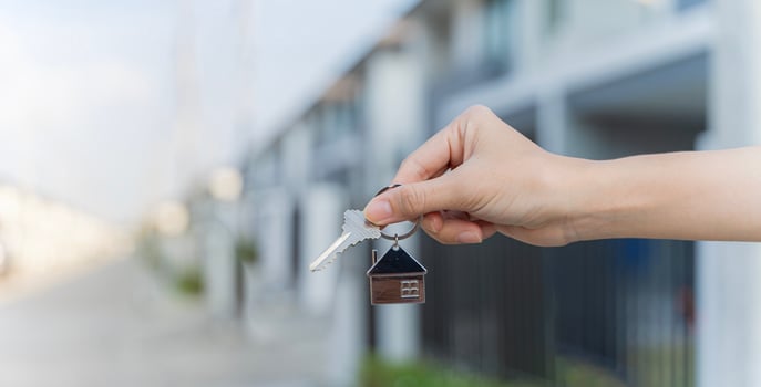 Crop close up of man hold show keys to own house buying first home from real estate agent. Male renter or buyer celebrate relocation moving to new home, make investment. photo