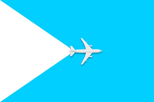 Flat lay of miniature toy airplane on white and yellow background. Travel items on a blue background. photo