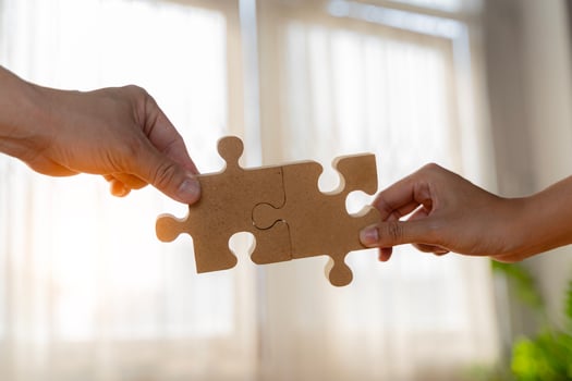 Business concept. Close up of hands connecting two pieces of jigsaw puzzle over the beautiful sunset photo