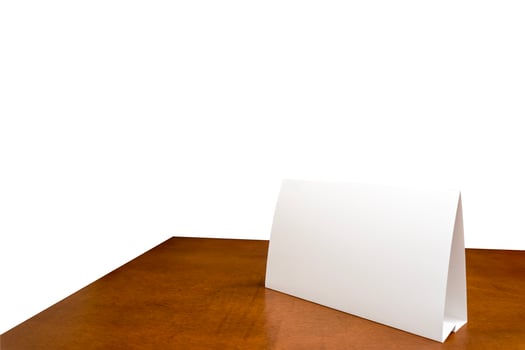 Blank paper table card on wooden table over white isolated background. Picture text can be inserted for advertising communication. photo