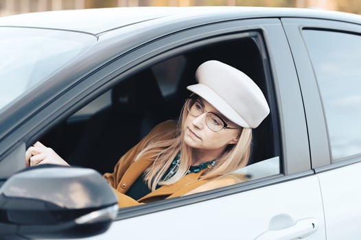 Middle-aged woman driver driving a car. Pretty female with hat and glasses, transport concept photo
