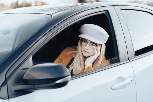 Middle-aged woman driver driving a car. Pretty female with hat and glasses, transport concept photo