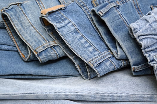 Lots of jeans pants in a stack. Denim background. photo