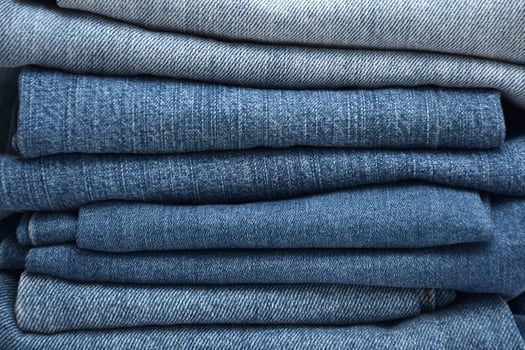 Lots of jeans pants in a stack. Denim background. photo