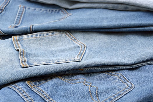 Lots of jeans pants in a stack. Denim background. photo