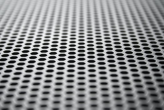 Perspective view on a the metal surface with regular round holes. Industrial background photo