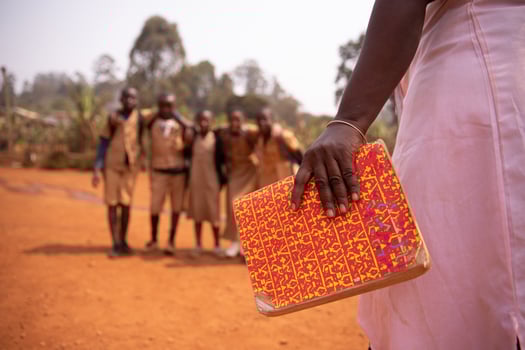 An african teacher is holding a book with her students out of focus in the background, concept of education in africa photo