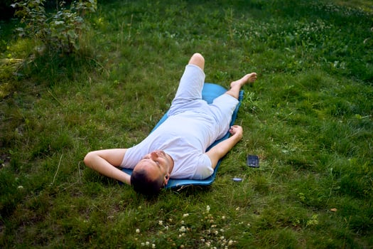 a man listens to a sound therapy playlist in headphones after somatic exercise in the morning in the garden photo