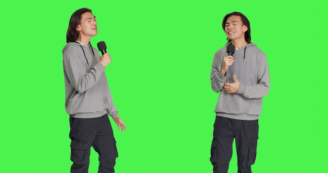Cool person doing karaoke session on camera, using microphone to sing modern songs and lyrics. Young adult having fun over greenscreen backdrop, creating music and singing tunes. photo