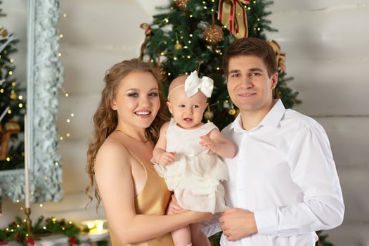 close-up portrait of a beautiful family, father and mother with a little daughter in their arms against the backdrop of a Christmas tree decorated for Christmas and New Year. happy family concept photo