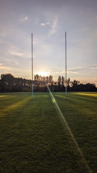 Rugby goalposts on a grassy field at sunset photo