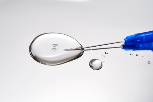 A drop of medicine flowing from a syringe with a needle. photo