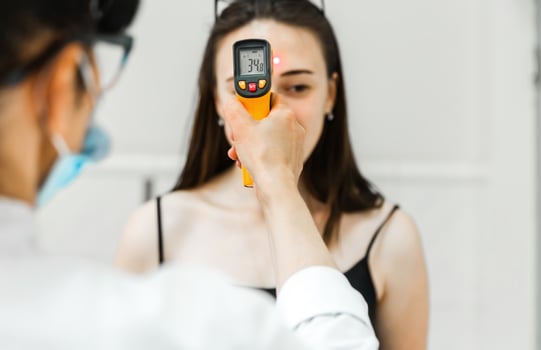 Healthcare Worker Checking Woman's Temperature with Infrared Thermometer photo