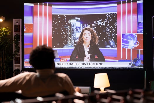 Cord cutter sitting on couch in front of widescreen smart TV displaying streamed news program. Person watching big television screen showing on demand channel with newscast coverage photo