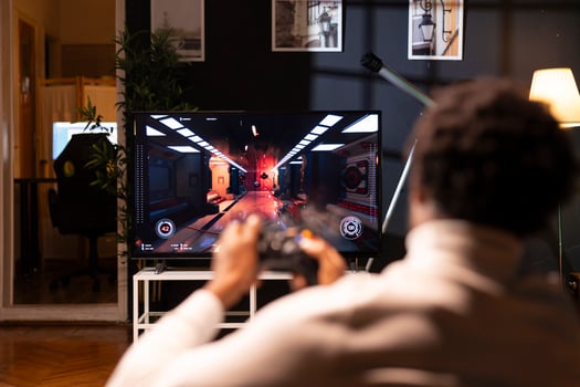Player using controller to play first person shooter videogame on smart TV, enjoying leisure time. Man in home theatre using high tech gaming console joystick to destroy flying robots photo