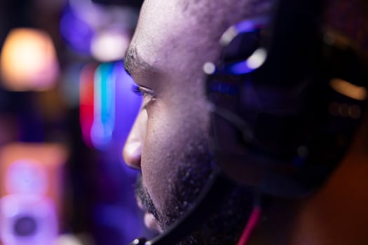 African american man wearing headphones playing game, teaching subscribers professional esport skills, close up shot. Media star using headset mic to chat with viewers, filming gaming tutorial photo