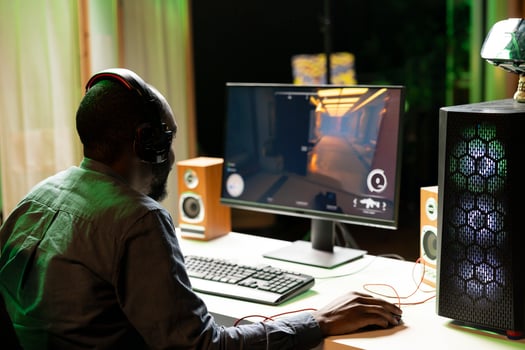 Man in dark living room playing science fiction videogame on gaming PC, concentrating on shooting foes. Gamer battling flying robots with futuristic gun in online singleplayer shooter photo
