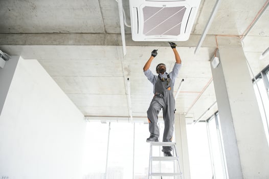 African American electrician repairing air conditioner indoors photo