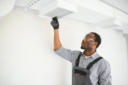 Industrial Theme. Warehouse Heating and Cooling System Installation by Professional Caucasian Technician. Commercial Building Ventilation Rectangle Canals. Air Distribution photo