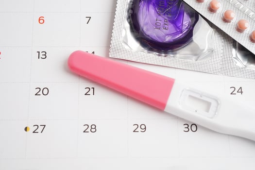 Pregnancy test with birth control pills and condom for female on calendar, ovulation day. photo