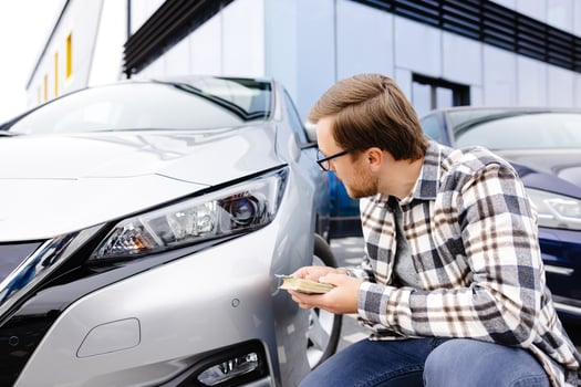 Young man holding money in hand standing front car and prepare pay by installments - insurance, loan and buying car concept insurance. Buy and down payment a car photo