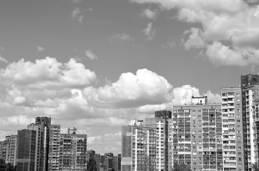 Apartment buildings under blue sky. Black and white monochrome grayscale photo background.