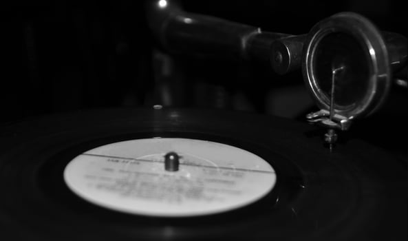 Black vinyl disc on a gramophone background. Black and white monochrome grayscale photo background.
