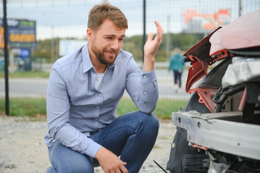 A frustrated man near a broken car. Grabbed my head realizing the damage is serious, the car is beyond repair photo
