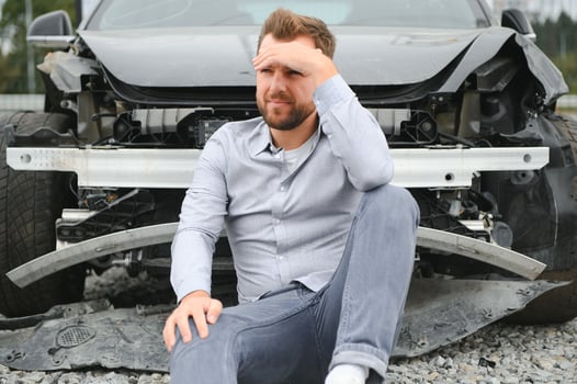 A frustrated man near a broken car. Grabbed my head realizing the damage is serious, the car is beyond repair photo