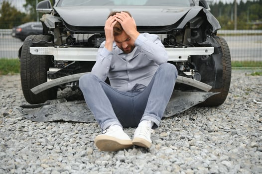 A frustrated man near a broken car. Grabbed my head realizing the damage is serious, the car is beyond repair photo