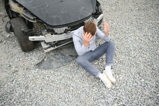 A frustrated man near a broken car. Grabbed my head realizing the damage is serious, the car is beyond repair photo