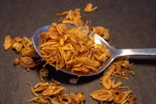 Crispy fried onions or roasted onion on the spoon on dark background photo