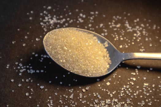 Brown sugar on the spoon with dark background photo