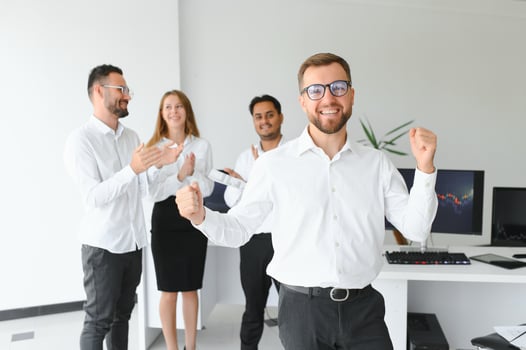 Team leader stands with coworkers in background photo
