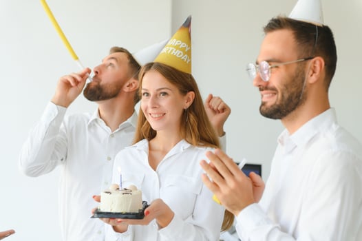 Happy businesswoman holding Birthday cake while making surprise party with her colleagues in the office. photo
