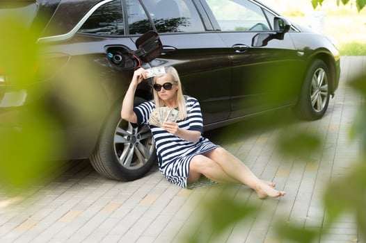 Desperate woman hold cash dollar bills next to car with an open tank, concept of rising fuel prices photo