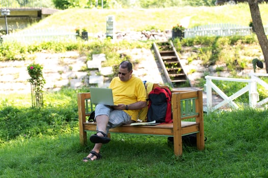 A man working and typing on laptop keyboard while sitting in the park, hand on laptop photo
