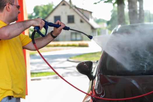 Car washing. Mature caucasian man cleaning automobile using high pressure jet water photo