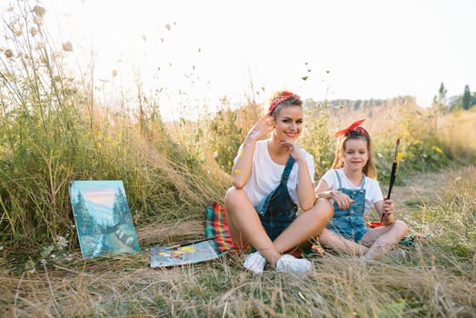 Sunny nature, mom and daughter paint a picture in a park , painting a Little Child, Child Creativity. Mother's Day. photo